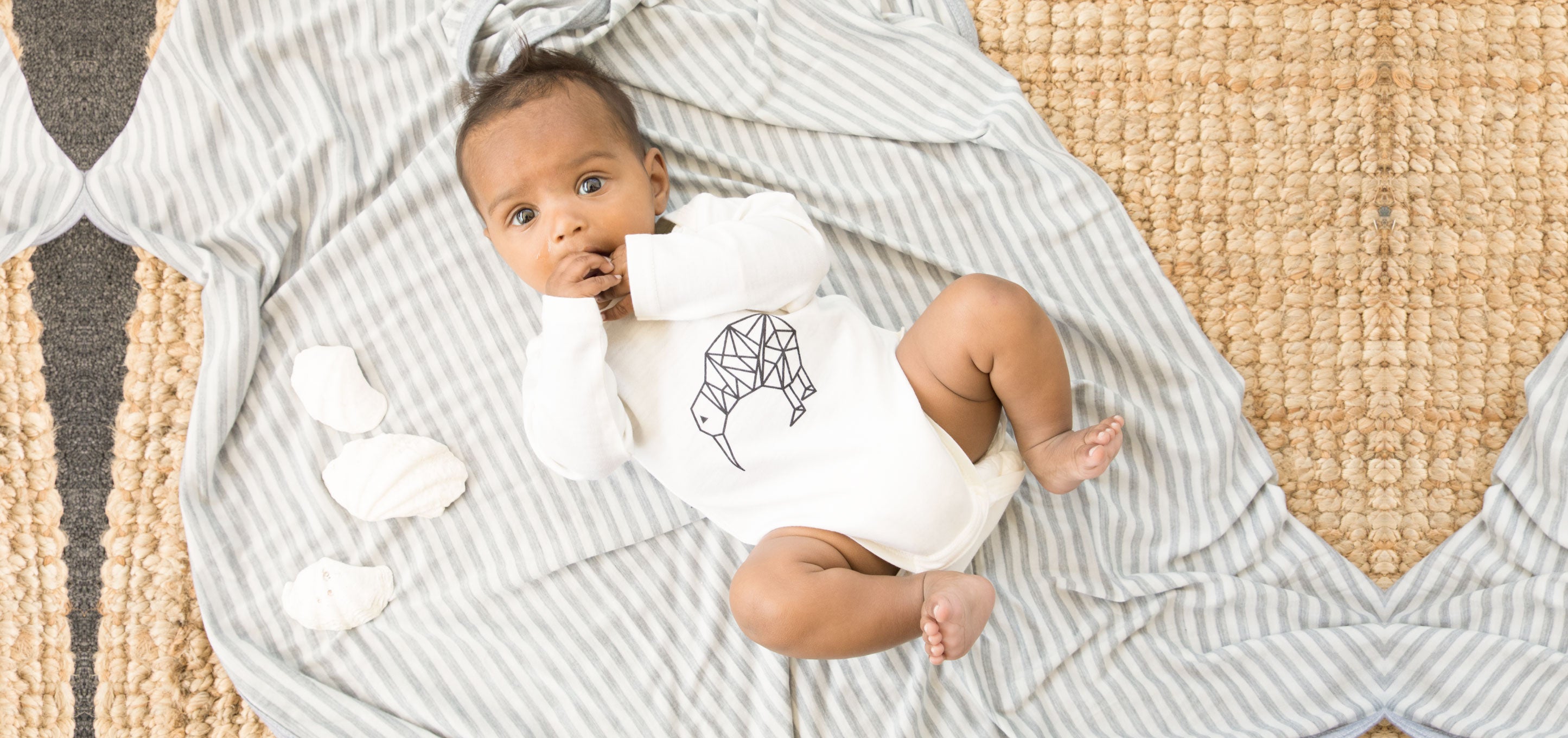 newborn on a merino blanket wearing a long sleeve bodysuit in lil kiwi colour from mokopuna merino