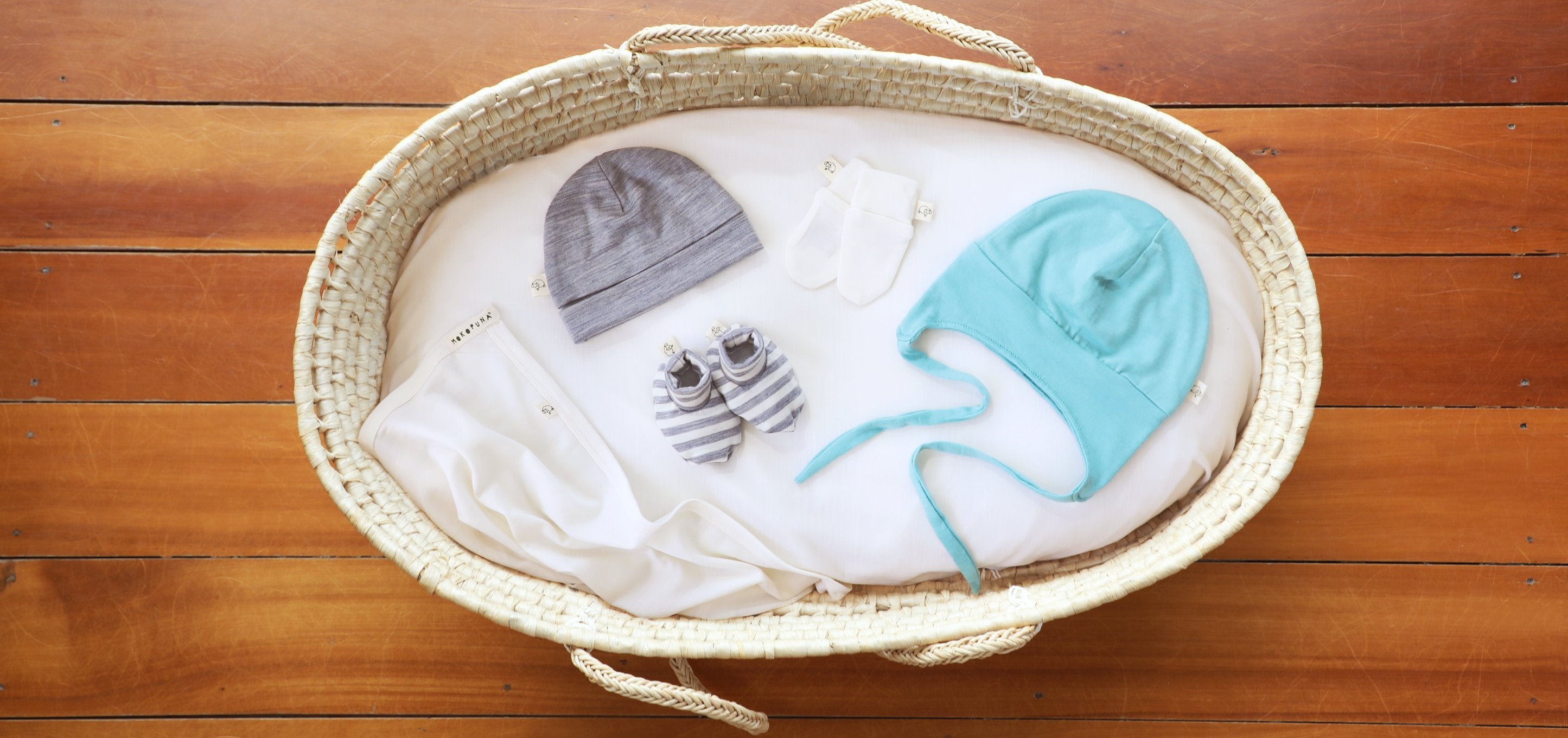 flat lay of merino accessories from mokopuna merino in a moses basket